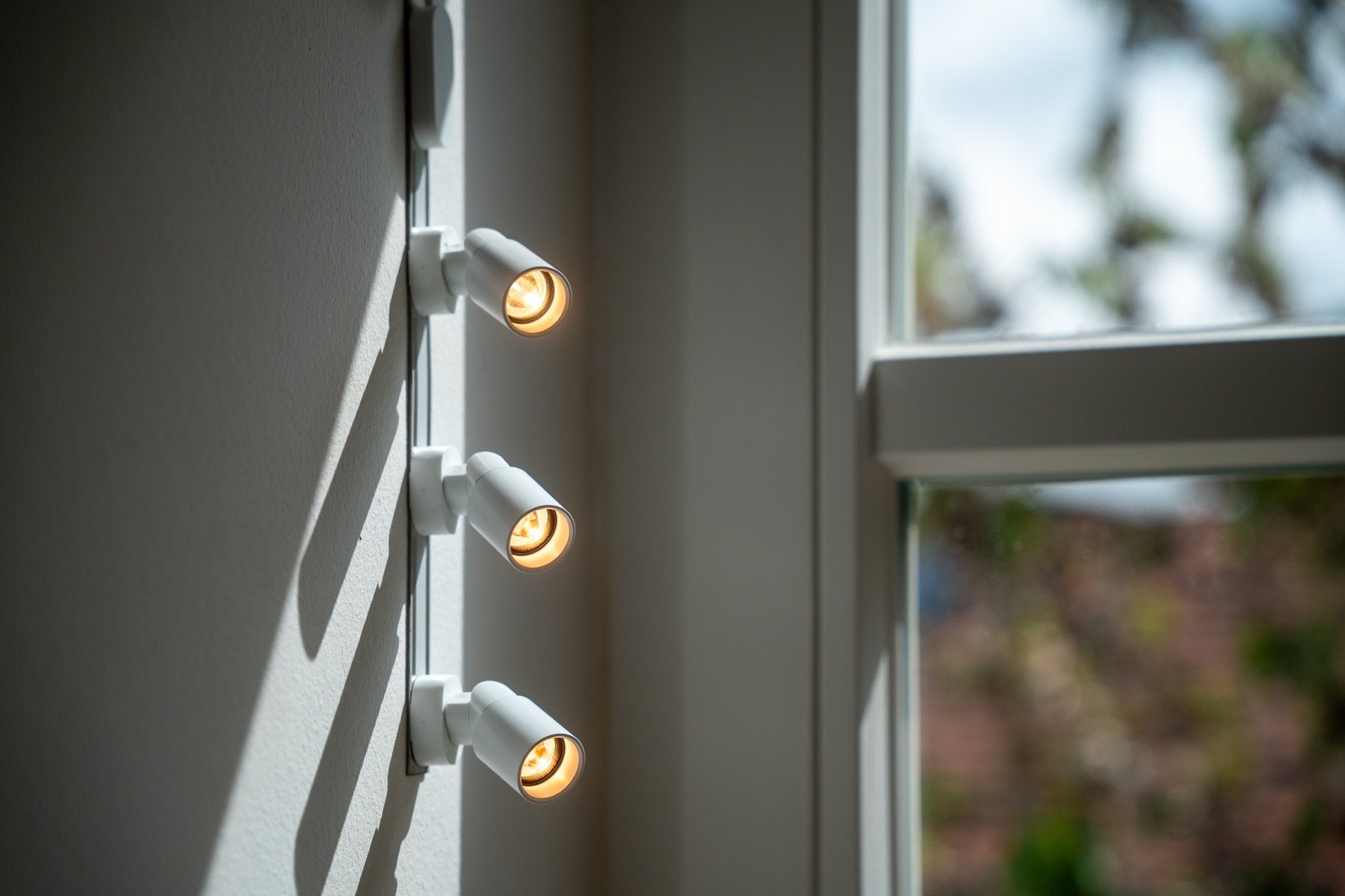 Three Light-IT spots on a rail beside a window